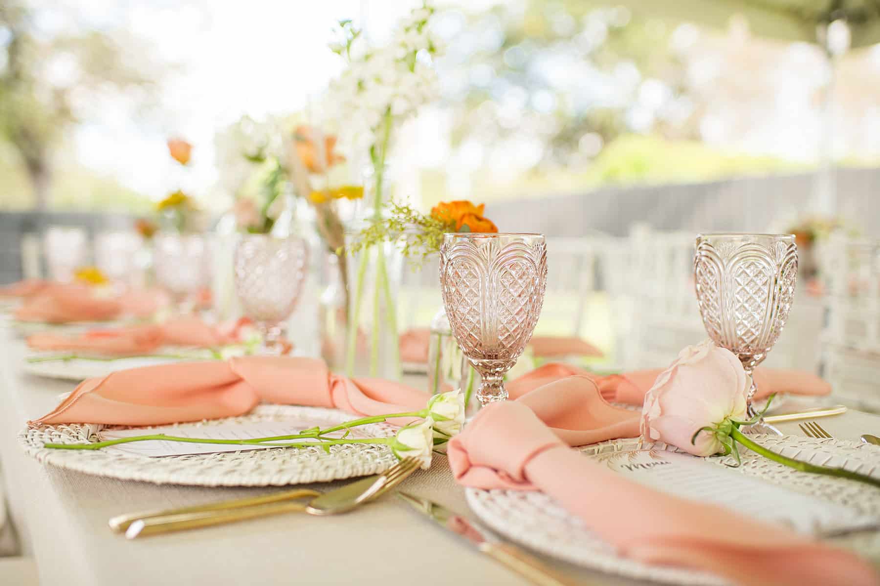 Event tabletop with peach colored linens and blush glassware